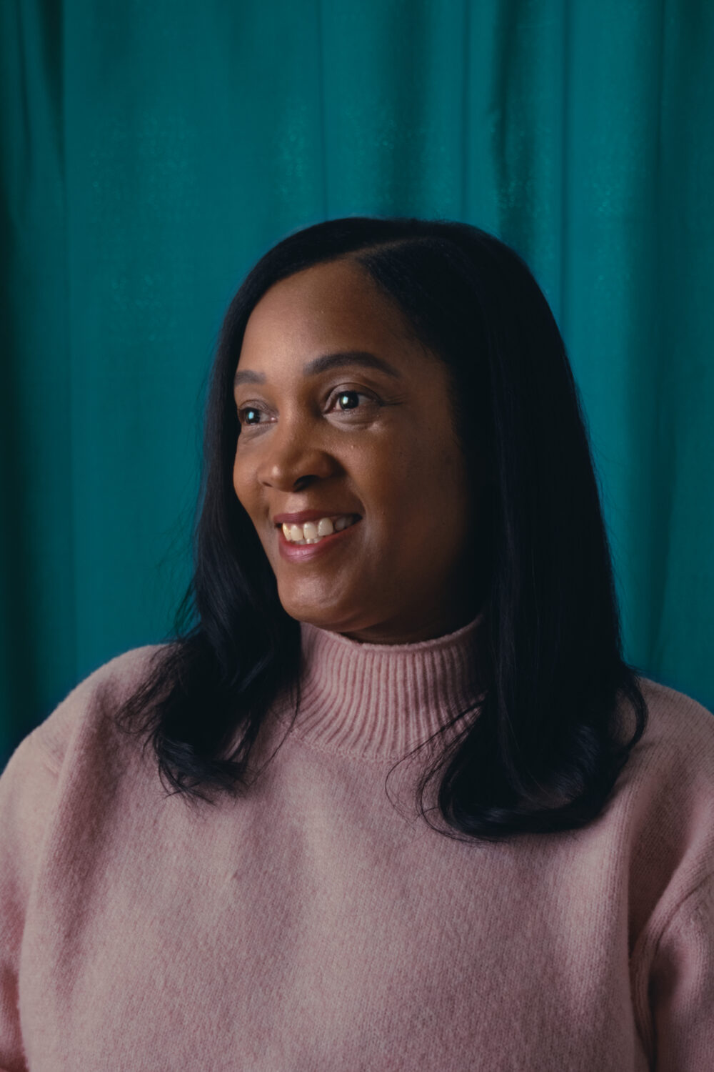 Leah, a 48 year old woman, looking to the left and smiling.